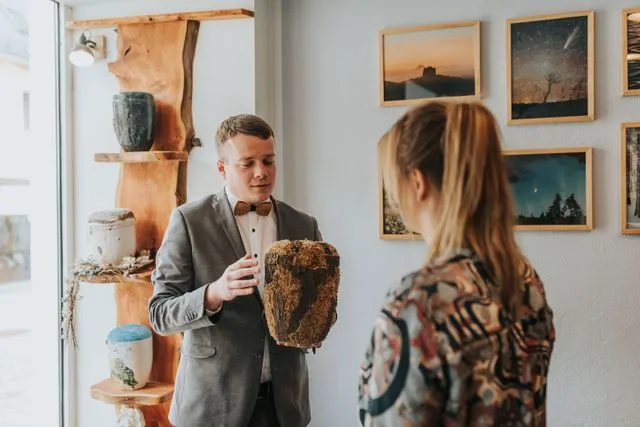 Bestatter Daniel Paul zeigt einer Angehörigen eine Urne im Beratungsraum des Bestattungshauses