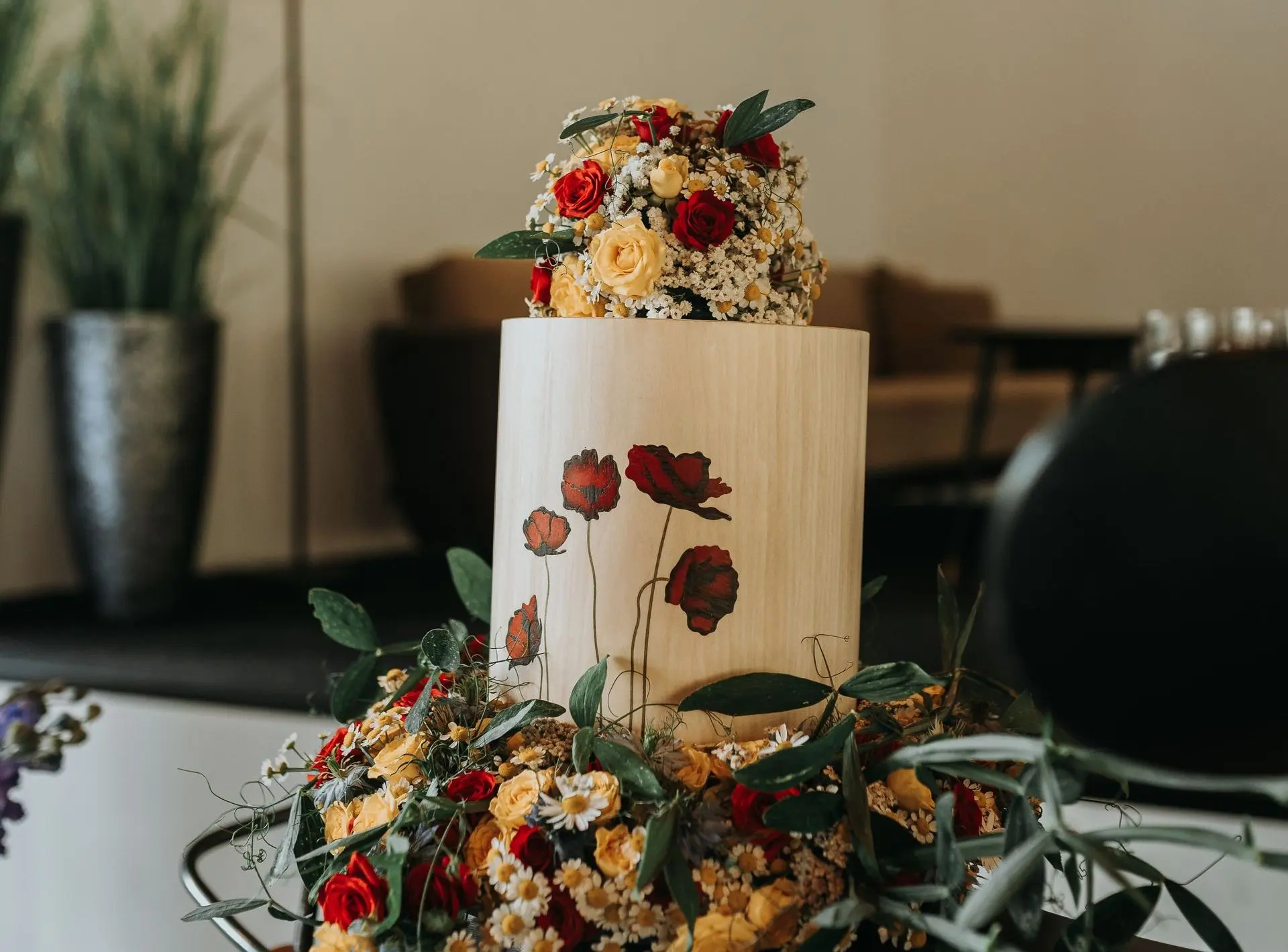 Holzurne mit handgemaltem Mohnblumenmotiv und floralem Urnenschmuck bei einer Trauerfeier einer Feuerbestattung