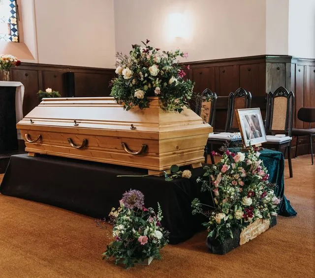 Sarg mit floralem Blumenschmuck in der Trauerhalle als Abschied bei einer Erdbestattung