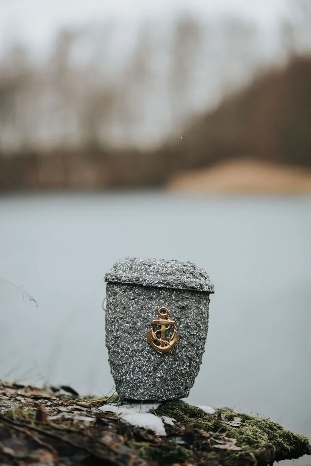 Seeurne mit Ankermotiv am Ufer als Symbol einer Seebestattung