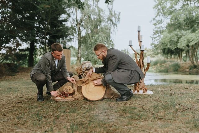 Zwei Bestatter arrangieren natürliche Trauerdekoration aus Holz bei einer Abschiedszermonie im Freien