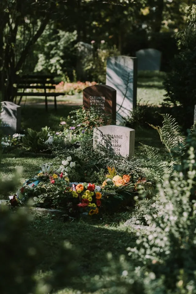 Grabstätte mit Grabstein und Blumenschmuck auf einem Friedhof als Ruhestätte einer Erdbestattung