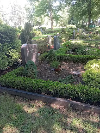 Gepflegte Grabanlage auf dem Friedhof Friedhof-Schoenau-Reichenbrand in Chemnitz mit Hecken, Blumenbeeten und Grabsteinen